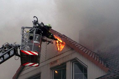 Offene Flammen schlagen aus dem Giebel, den ein Feuermann mit der Axt öffnet.