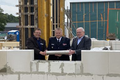 Fachdienstleiter Uwe Koltzau (von links), Kreiswehrführer Stefan Mohr und Kreispräsident Helmuth Ahrens mit einer Kapsel, die ins Mauerwerk des neuen Gebäudes eingelassen wurde. Foto: Katja Wohlers